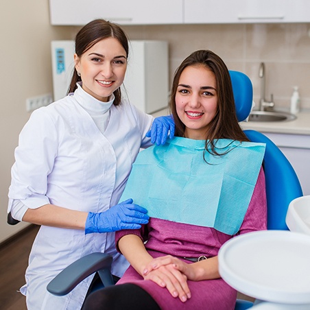 Dentist and female teenager smiling after appointment