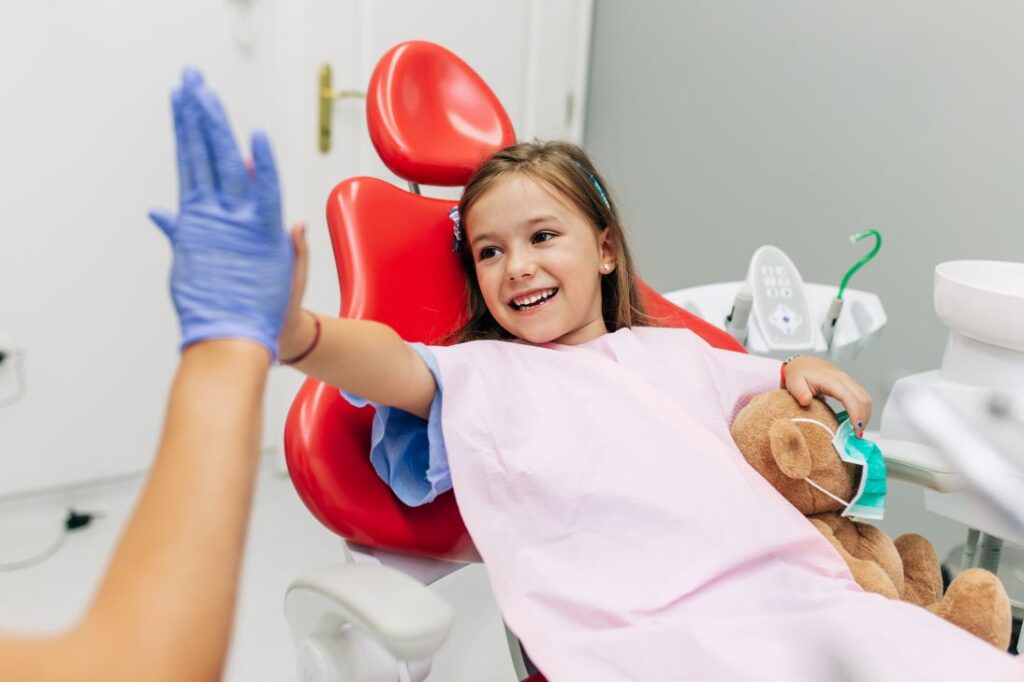 A little girl giving a high five to a dentist.