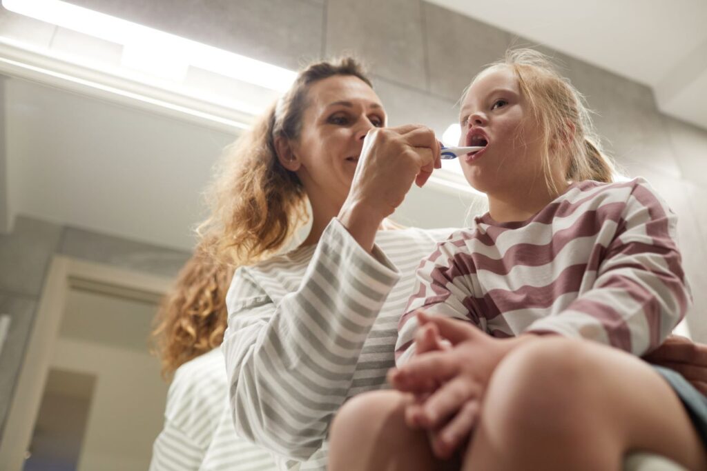 A mother brushing the teeth of a girl with Down Syndrome.